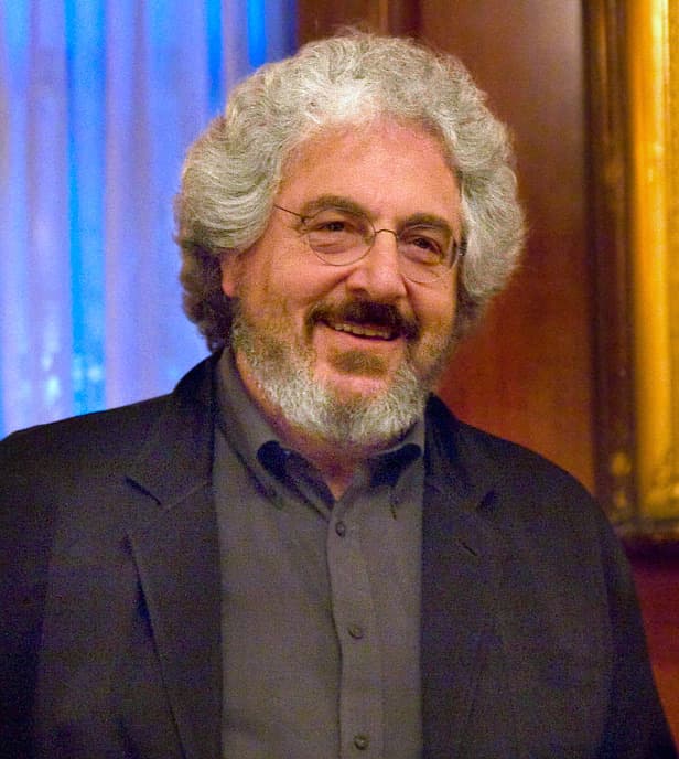 Harold Ramis, grey curly hair and beard, smiling in a dark jacket