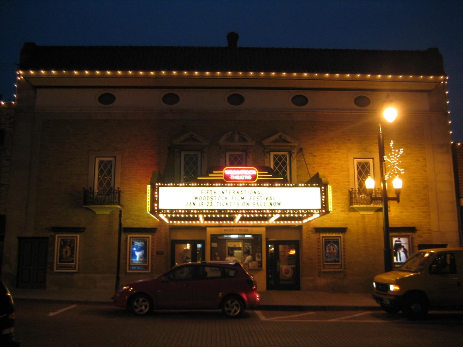 A lit theatre marquee under strings of lights on a dark street