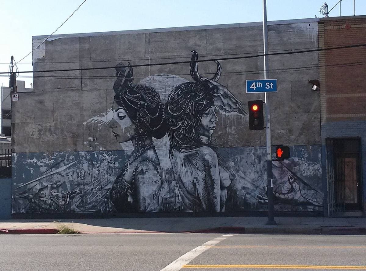 A large mural on a warehouse wall at a corner with a 4th St sign