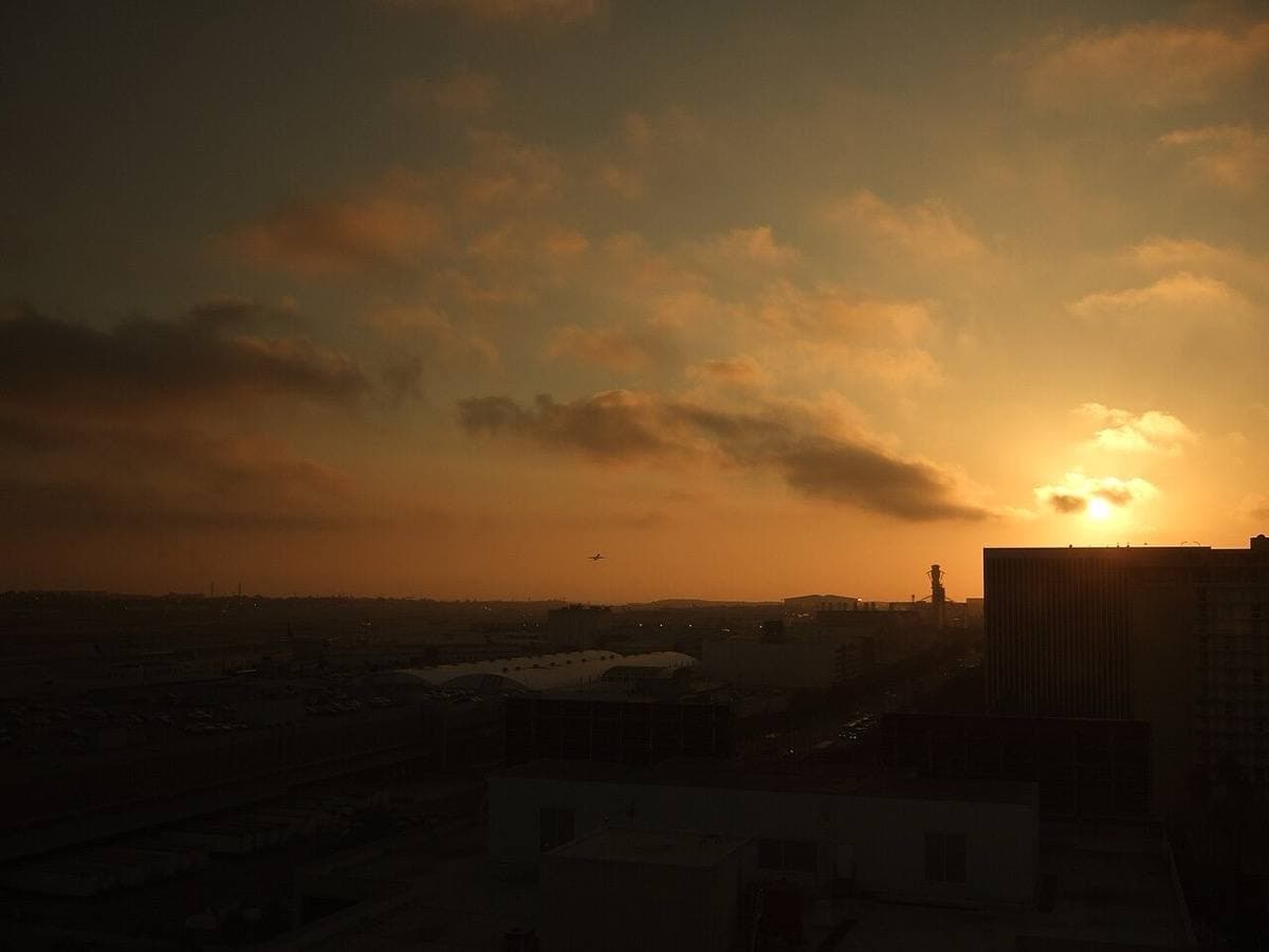 A dusk sky over dark rooftops near the airport
