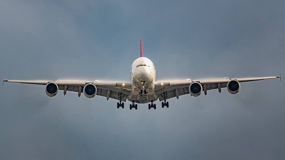 A four-engined airliner head-on with its wheels down against a grey sky