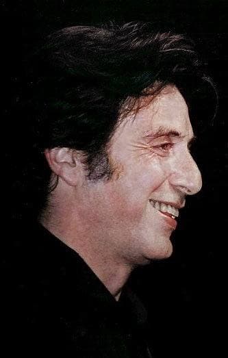 Al Pacino in profile, smiling, against a dark background