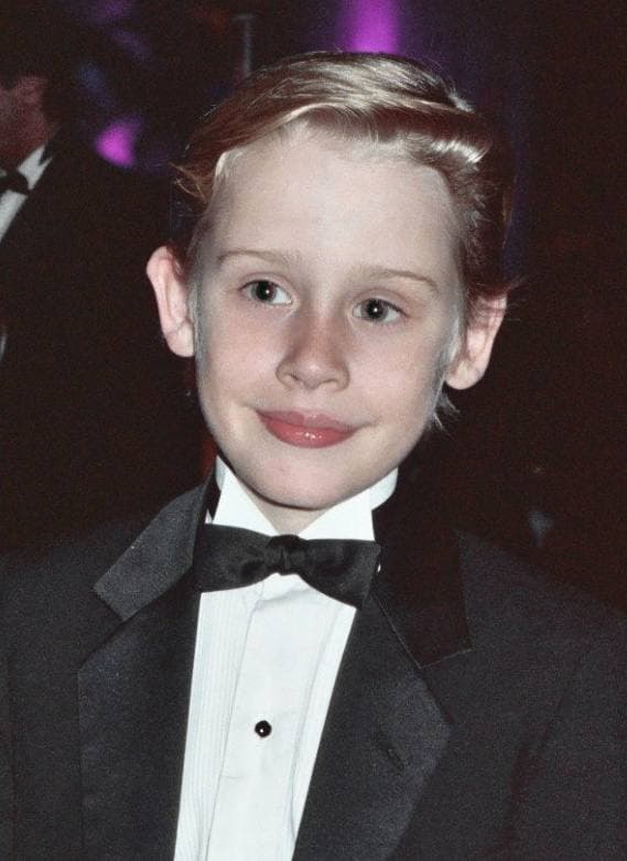 A smiling boy with fair hair in a dinner jacket and bow tie