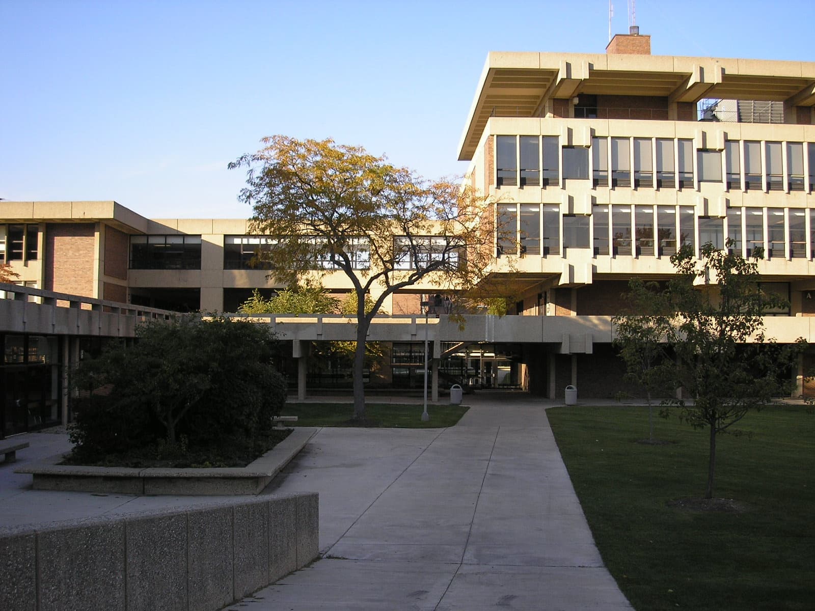 Low modernist school buildings beside a lawn and paths