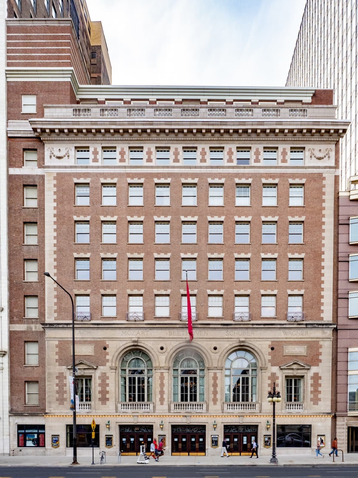 A brick and stone concert hall front with three arched windows