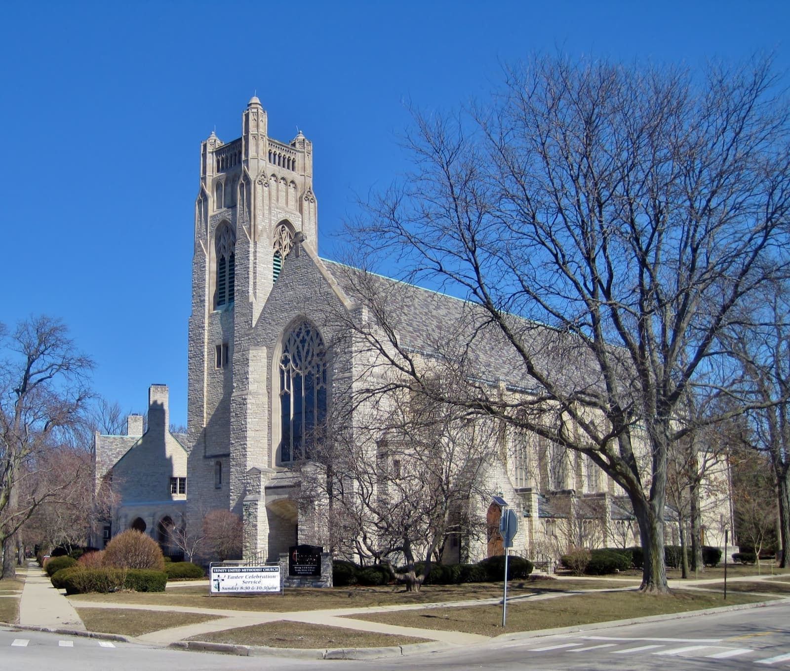 A grey stone Gothic church with a square tower under a blue sky