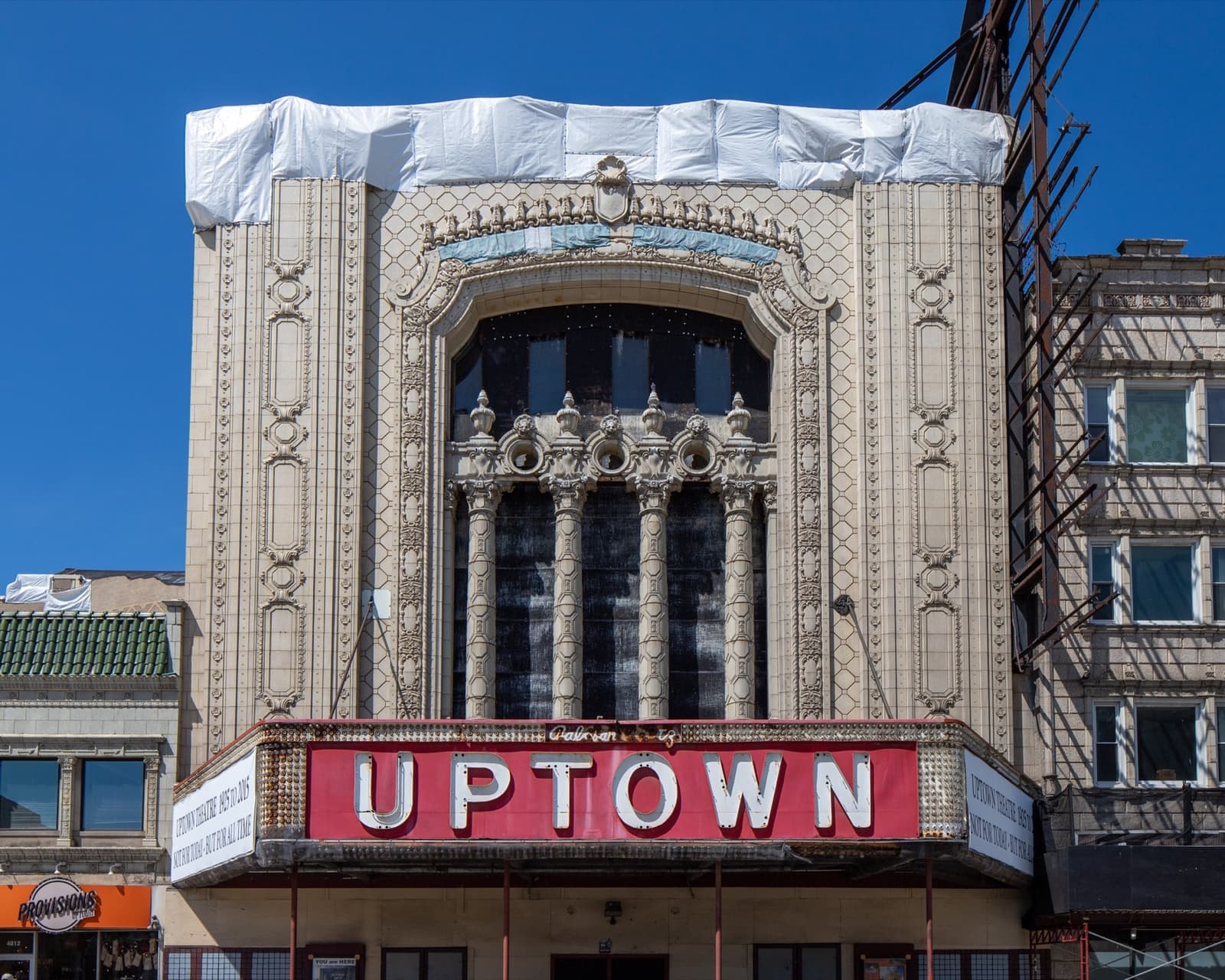 A tall cream terracotta theatre front above a red UPTOWN sign