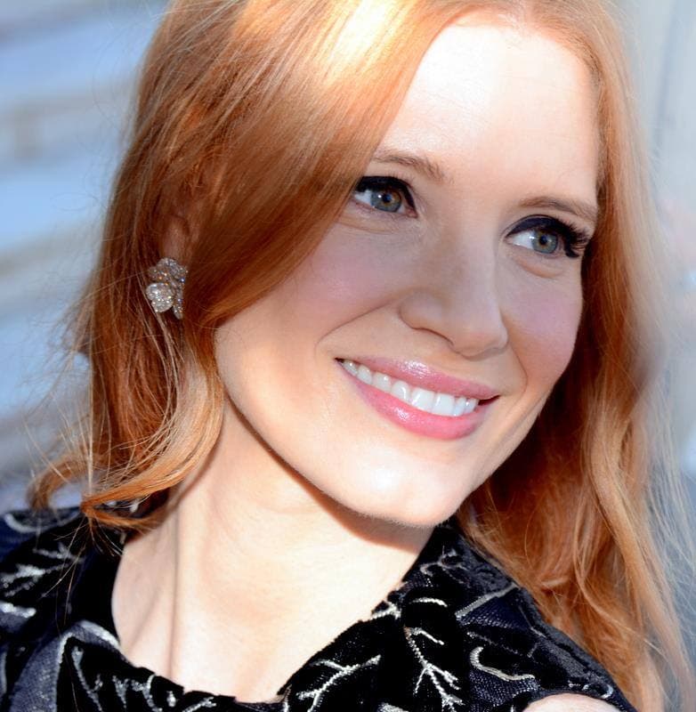 Jessica Chastain with red hair, smiling, in close-up