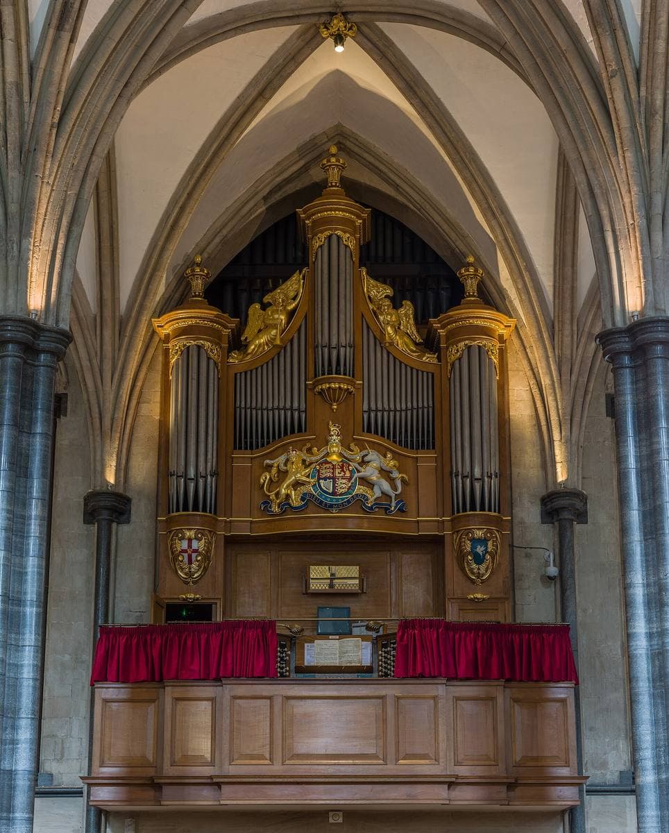 A gilded organ case above red-cushioned stalls in a Gothic church
