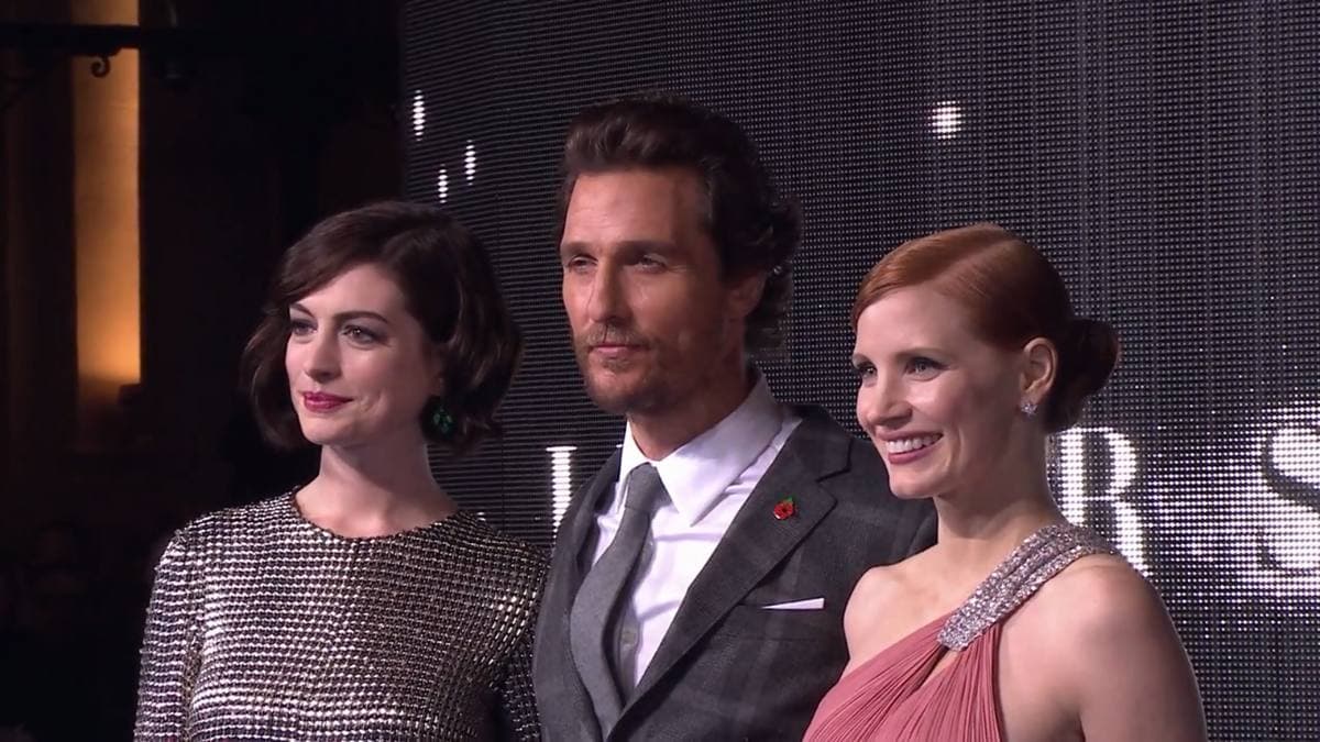 Anne Hathaway in a silver dress, Matthew McConaughey in a dark suit and Jessica Chastain in pink, standing together at a premiere
