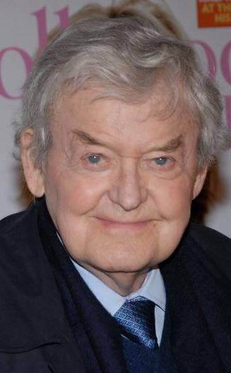 Hal Holbrook, white-haired, smiling, in a dark coat and tie