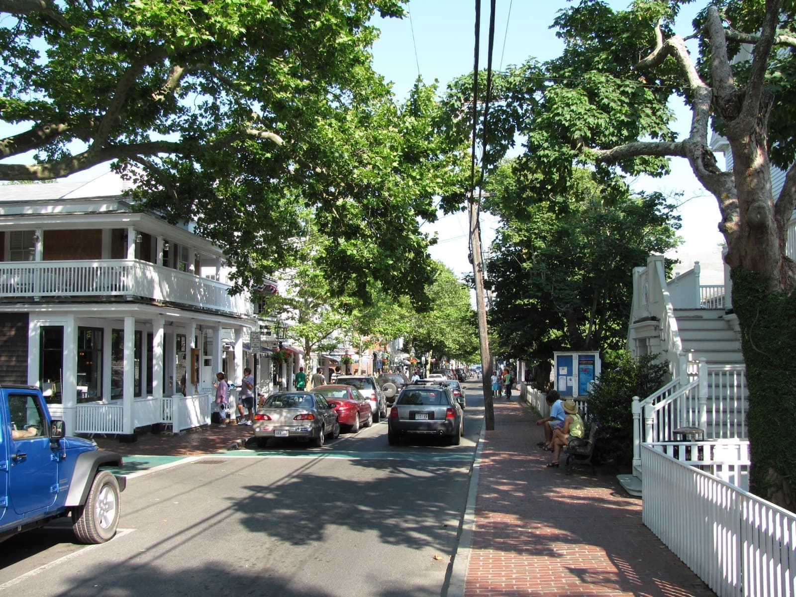 A tree-lined Main Street in Edgartown with white clapboard shops and brick pavements