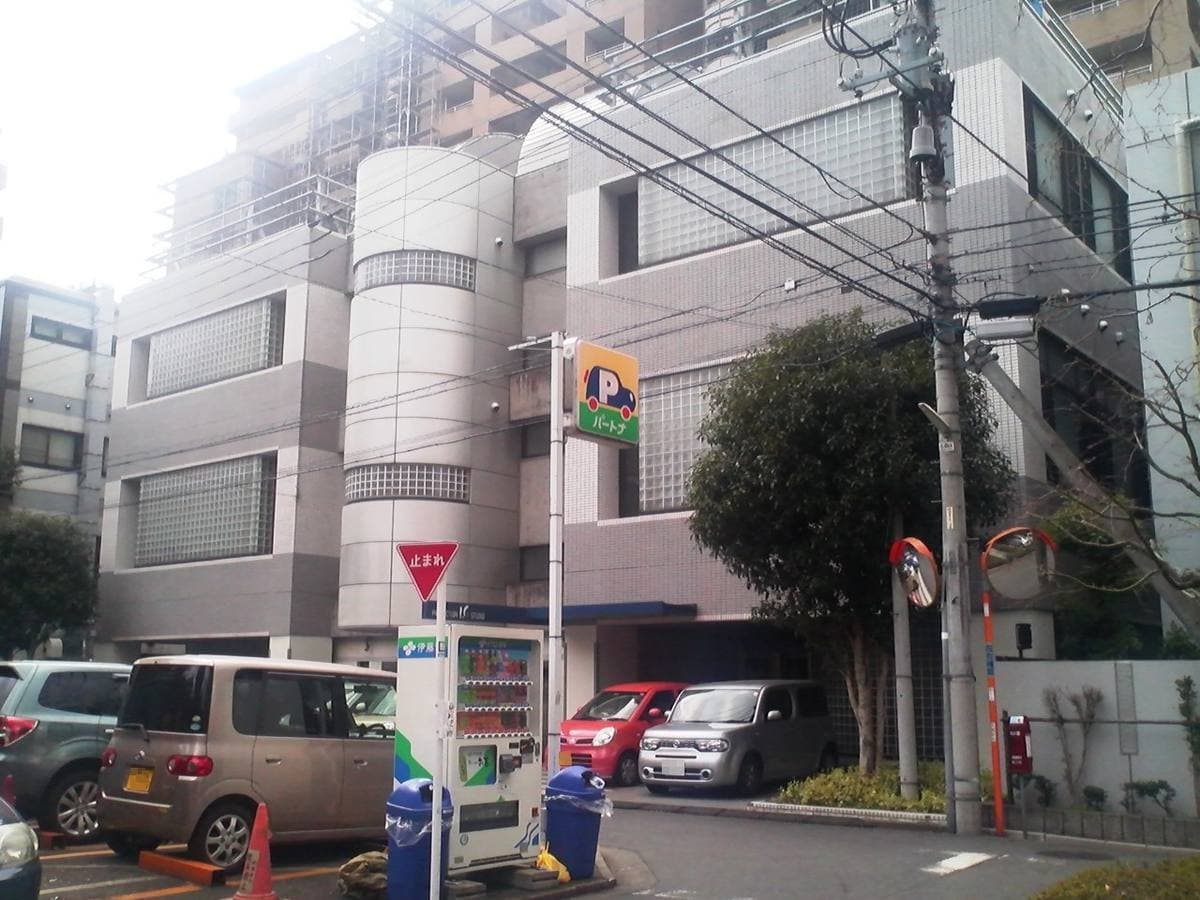 A pale modern office building on a quiet street corner with a vending machine outside