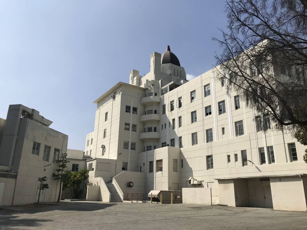 A white stepped Art Deco hospital block with a small dome, against a blue sky