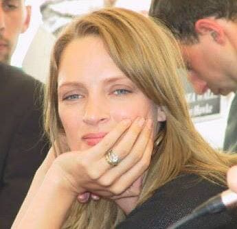 Uma Thurman, chin on her hand, smiling slightly