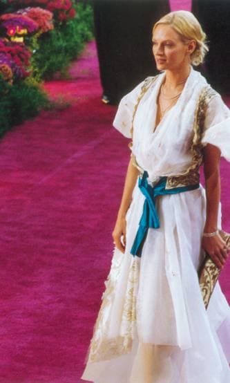 Uma Thurman in a long white dress with a blue sash on a purple carpet