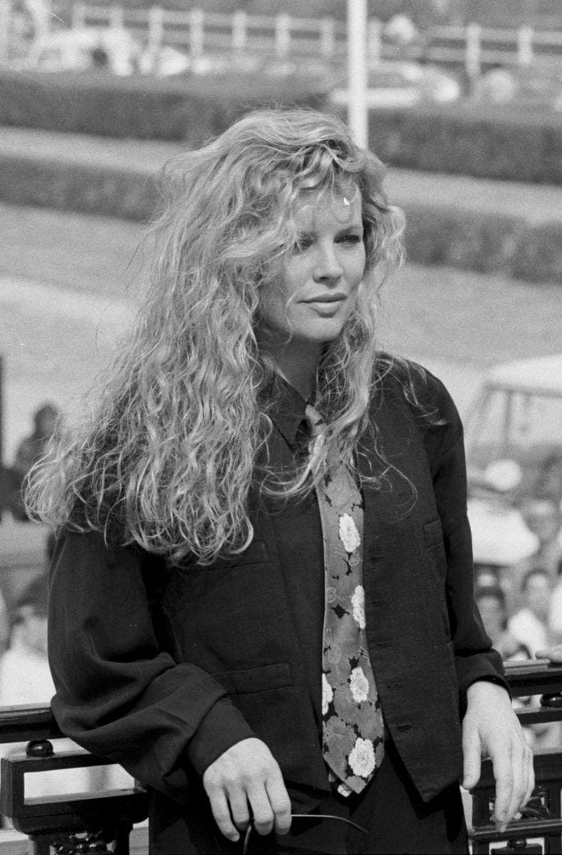 Kim Basinger in black and white, long fair hair, a patterned tie over a dark shirt