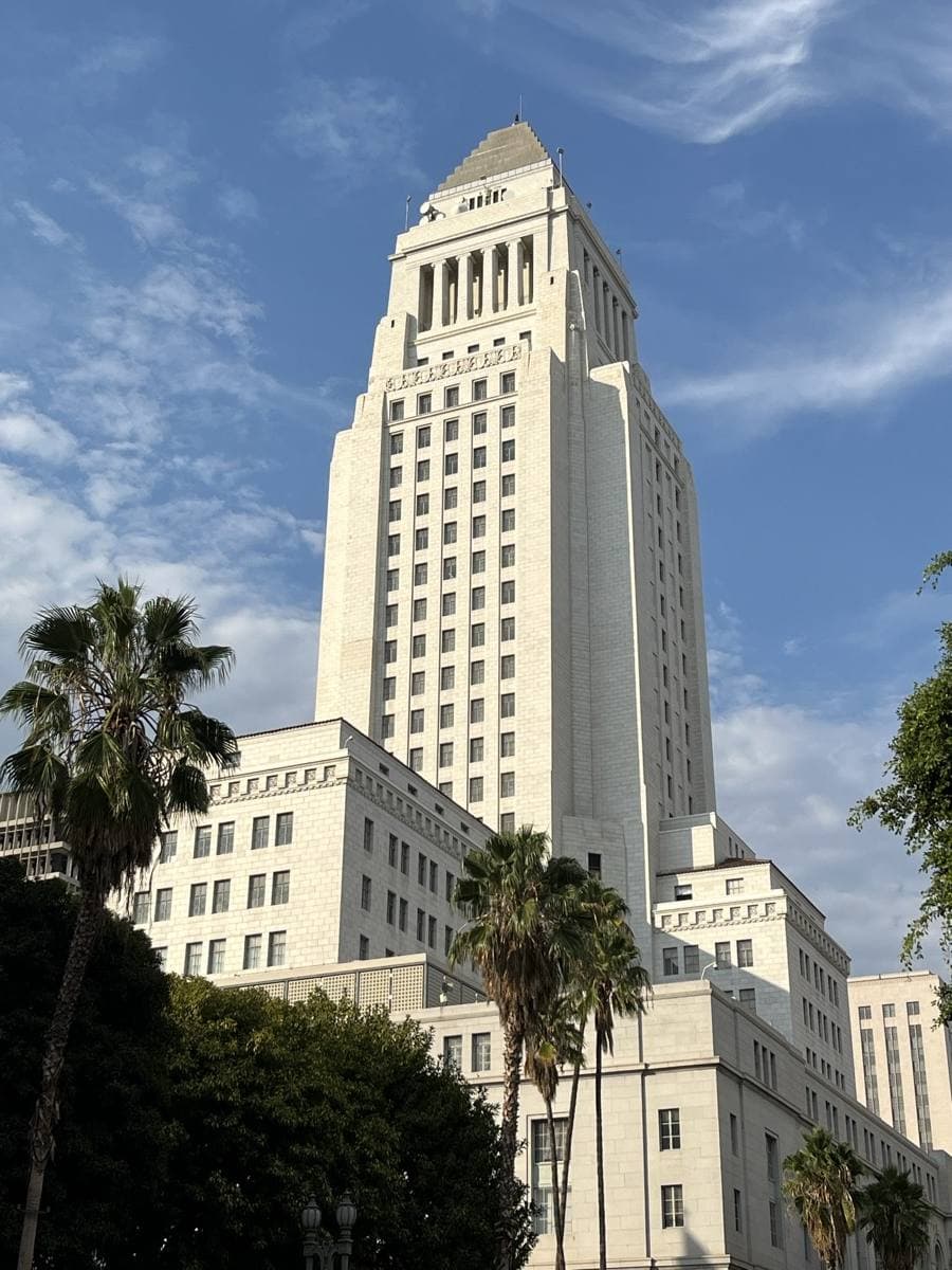 The white stepped tower of Los Angeles City Hall against a blue sky