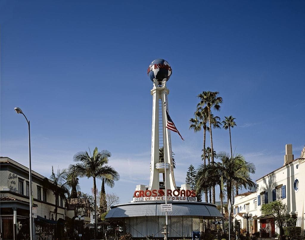 A white tower topped with a globe over a low streamlined building and palms