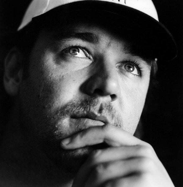 Russell Crowe in black and white, in a cap, chin resting on his hand