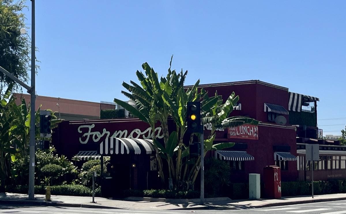 The red Formosa Cafe with its script sign and striped awnings among palms