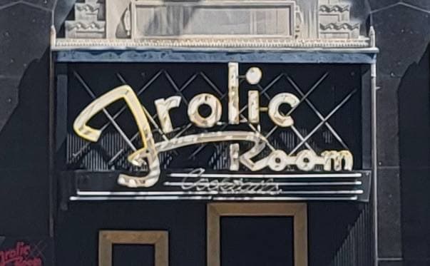 The Frolic Room's script sign over a black door