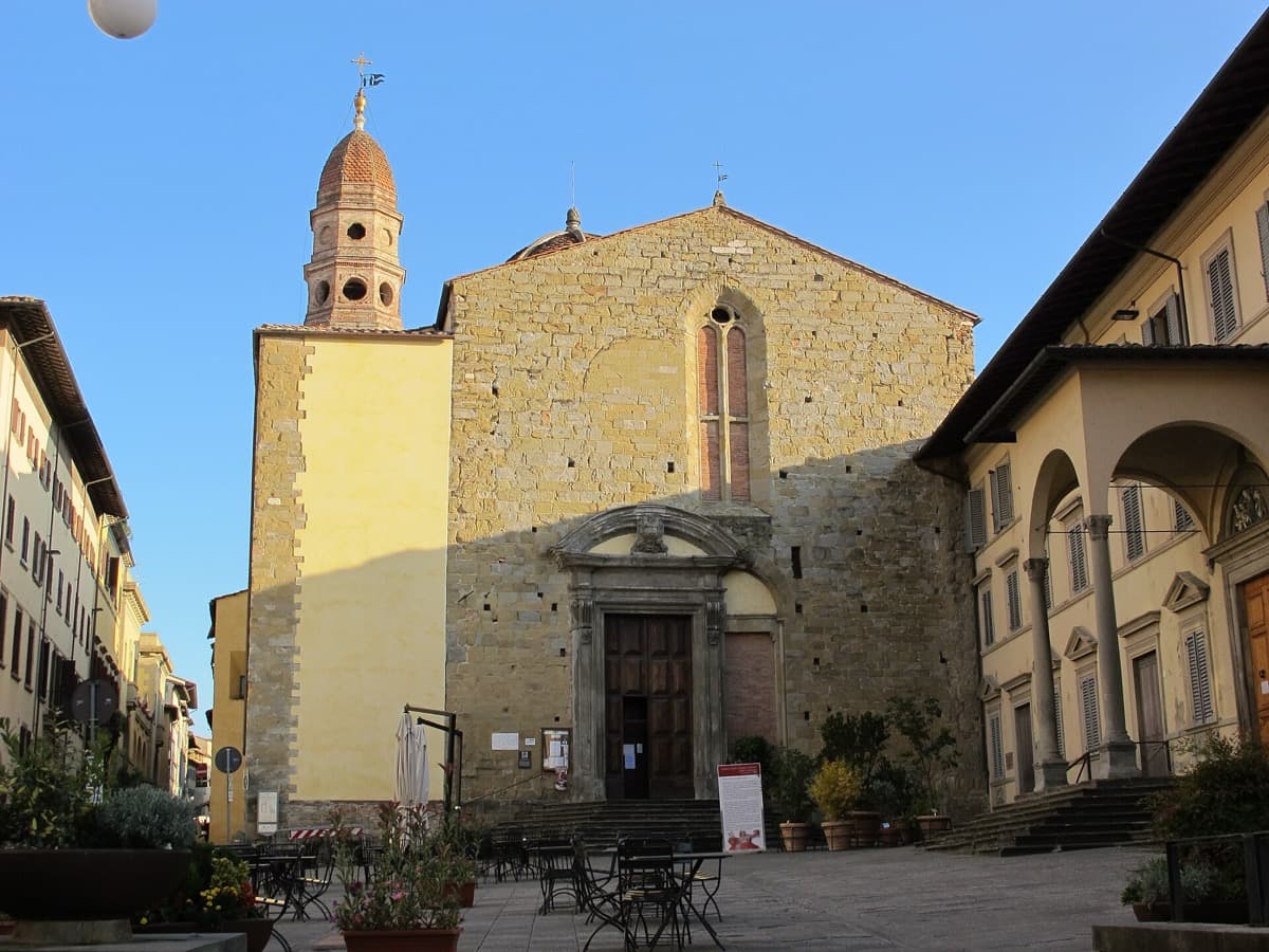 Plain stone abbey front with a bell tower beside a quiet square