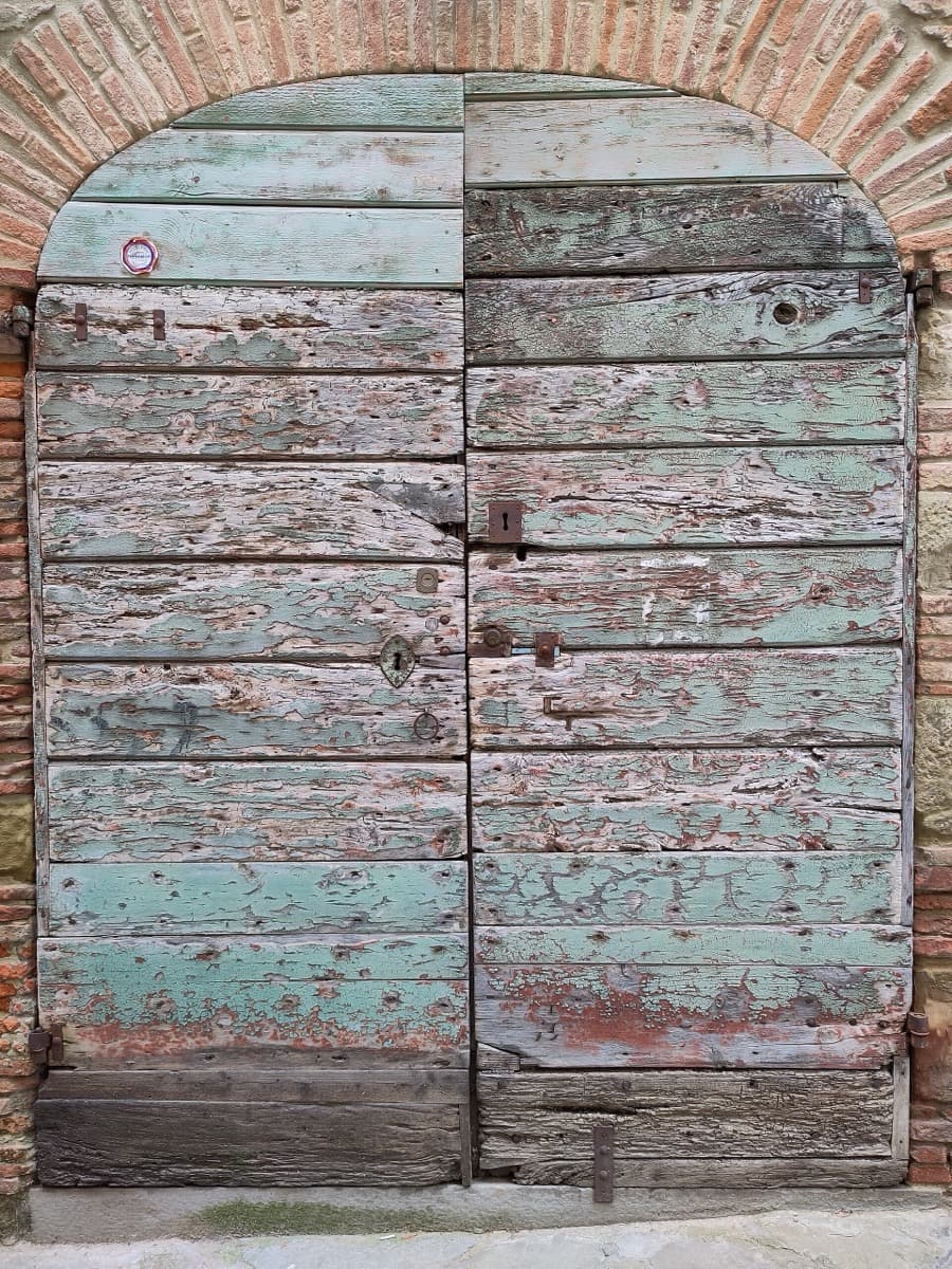 Narrow old street with wooden doors in stone walls
