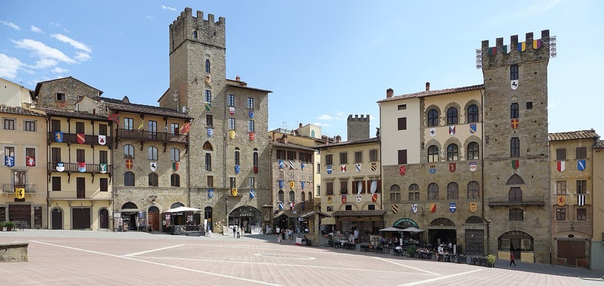 Wide sloping stone square lined with tall old buildings and a loggia