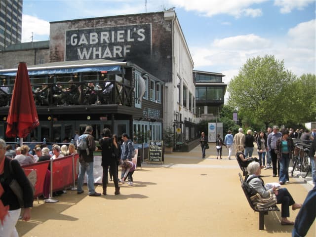 Benches on the riverside walk below the painted Gabriel’s Wharf sign