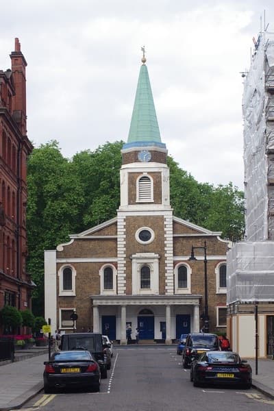 A plain Georgian chapel with a white portico and a slim green spire