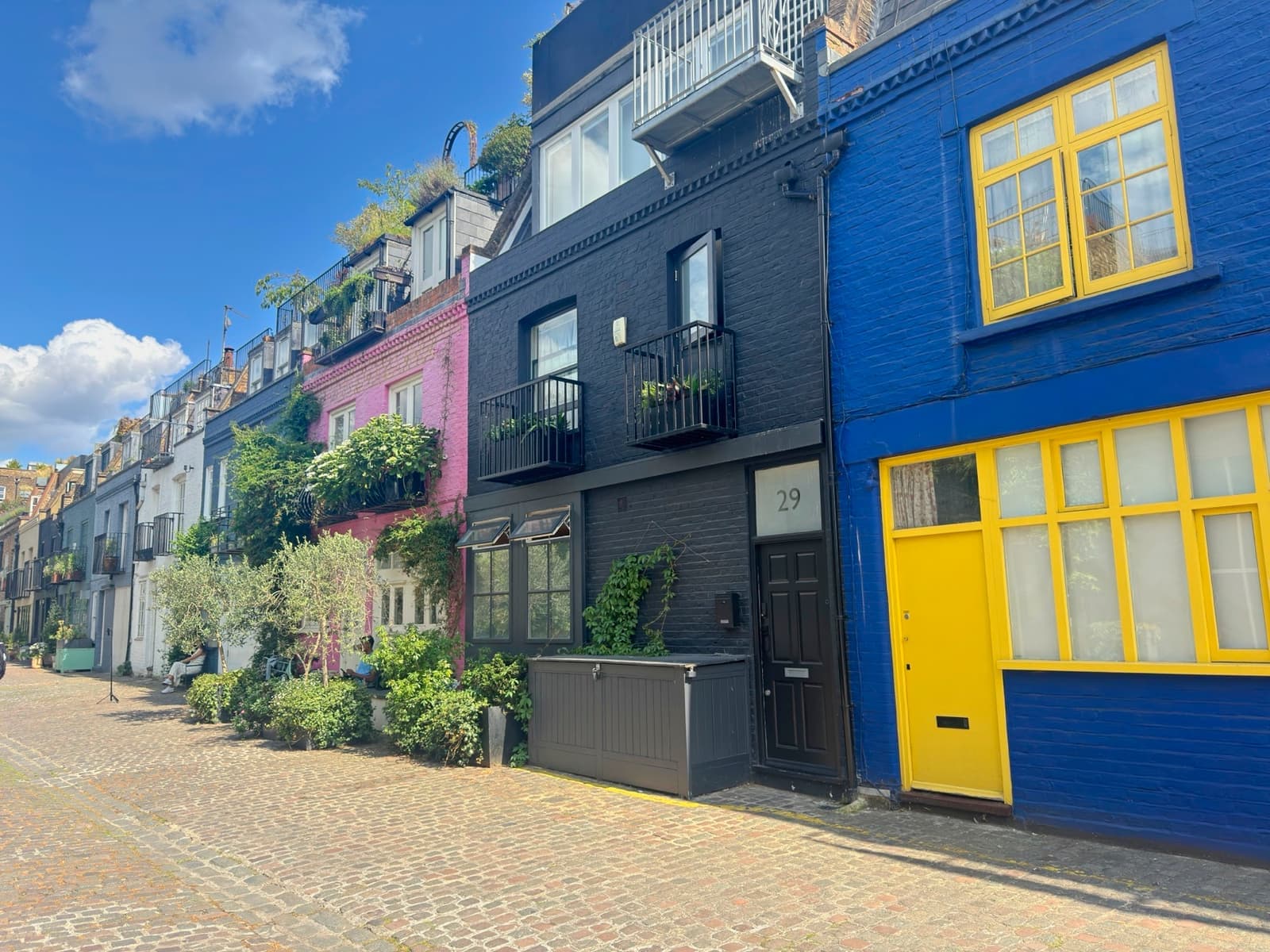 A cobbled mews of brightly painted houses, one blue with yellow windows