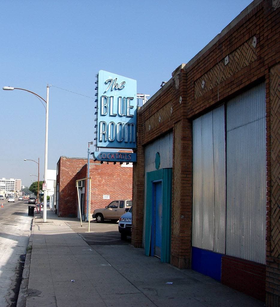 A brick bar front with a blue neon sign reading The Blue Room