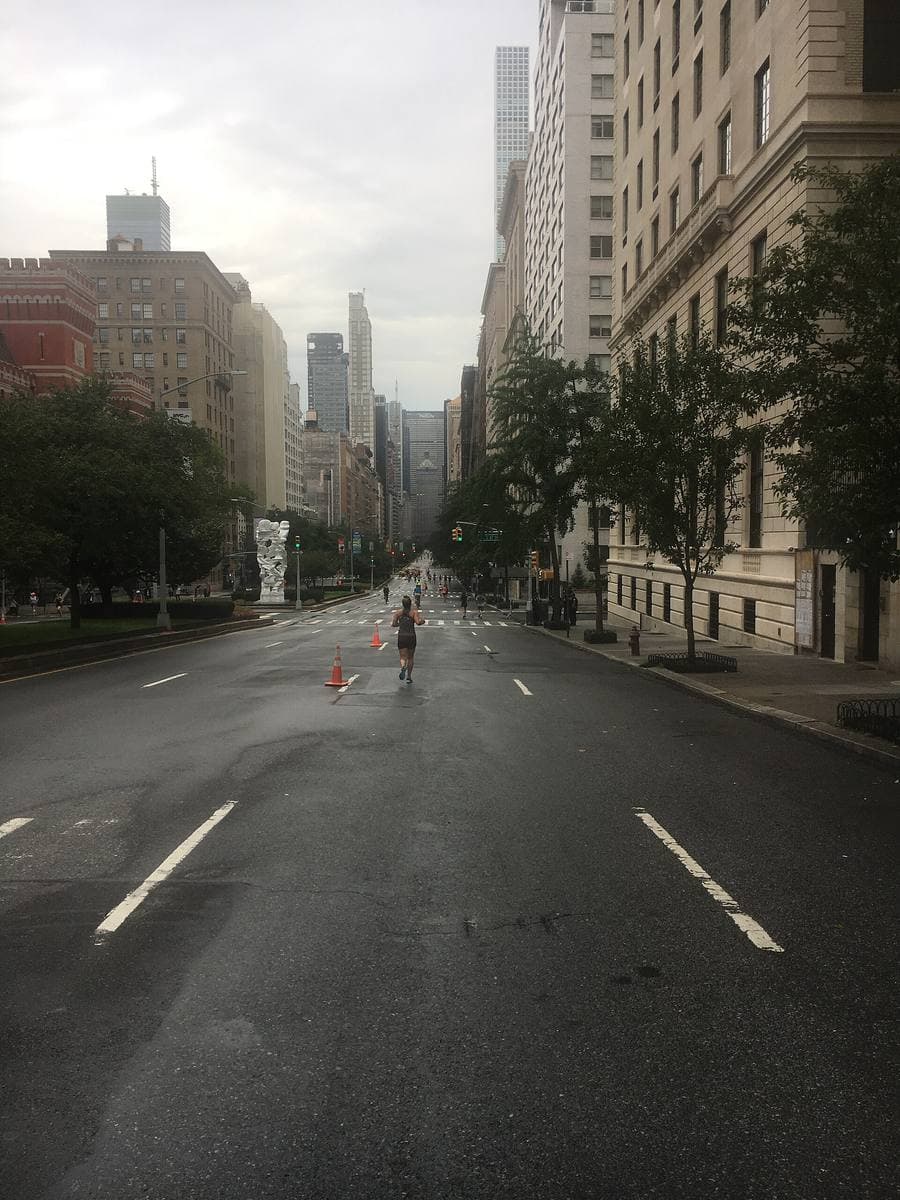 An empty wide avenue between apartment blocks, a tower closing the view