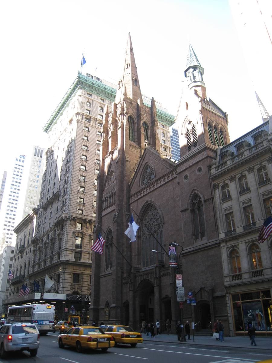 A tall hotel with a green copper roof next to a brownstone church spire