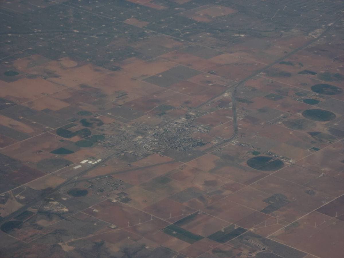 Flat West Texas farmland in squares and circles around a small town, seen from a plane