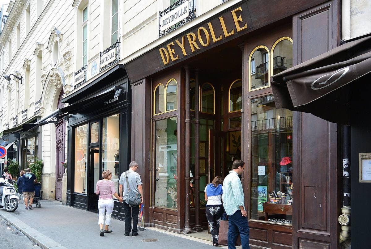 The dark wooden shopfront of Deyrolle with its gold lettering, people walking past on the pavement