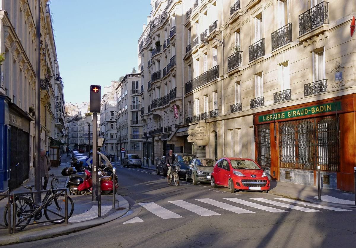 A quiet Paris street junction with a bookshop on the corner and tall apartment buildings