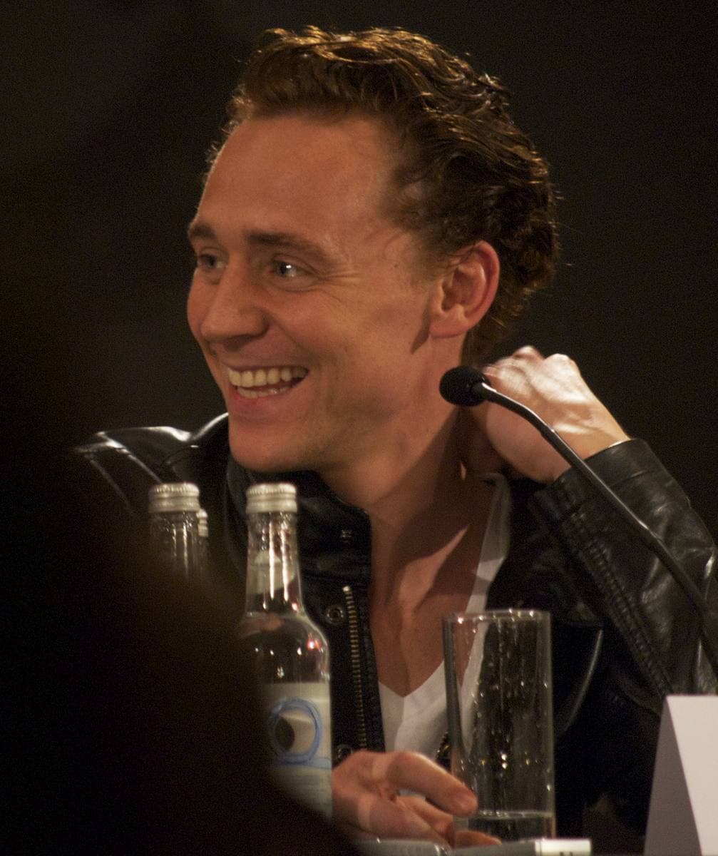 Tom Hiddleston smiling at a press-conference table