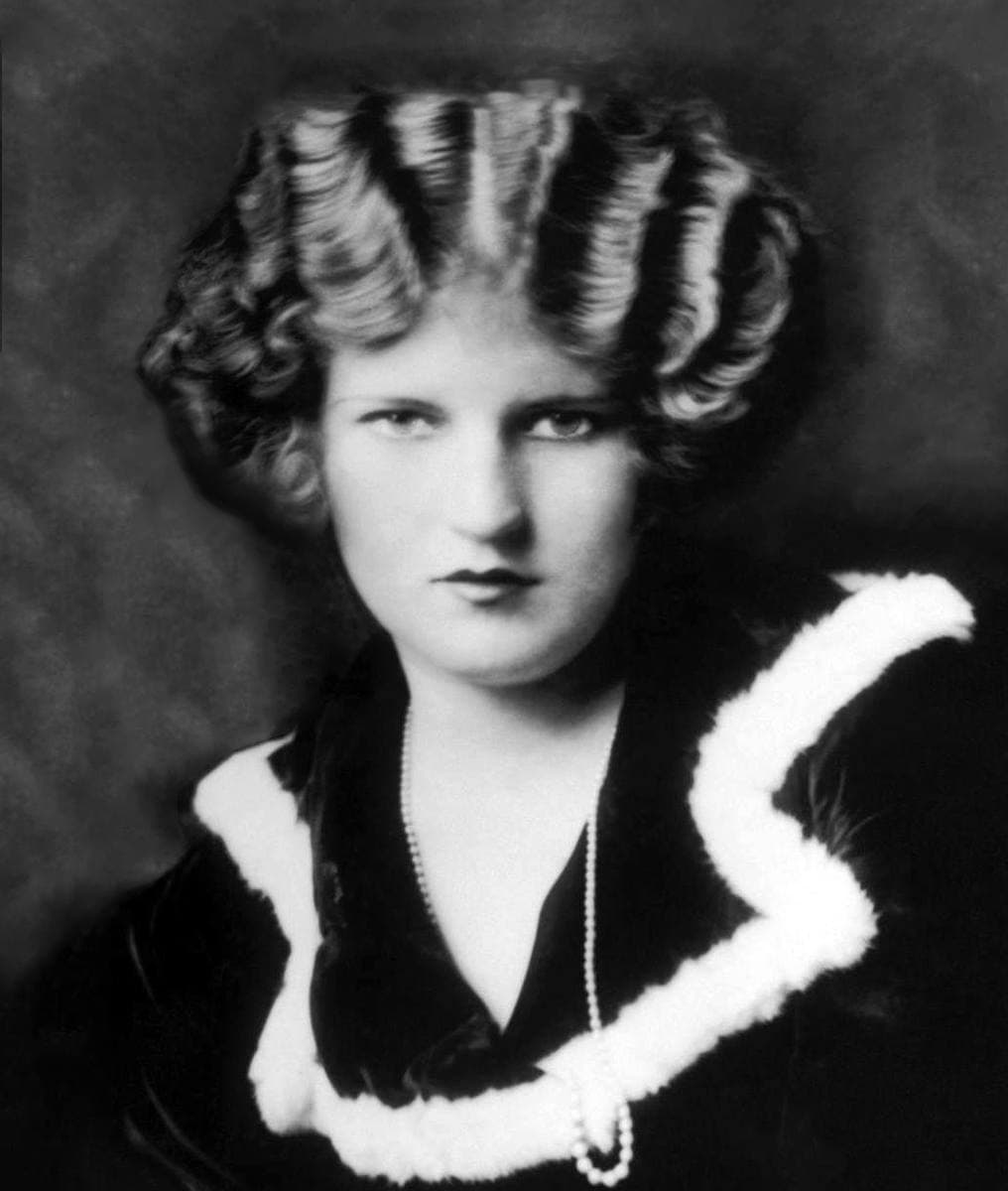 A black-and-white portrait of Zelda Fitzgerald with sculpted curls and a fur collar