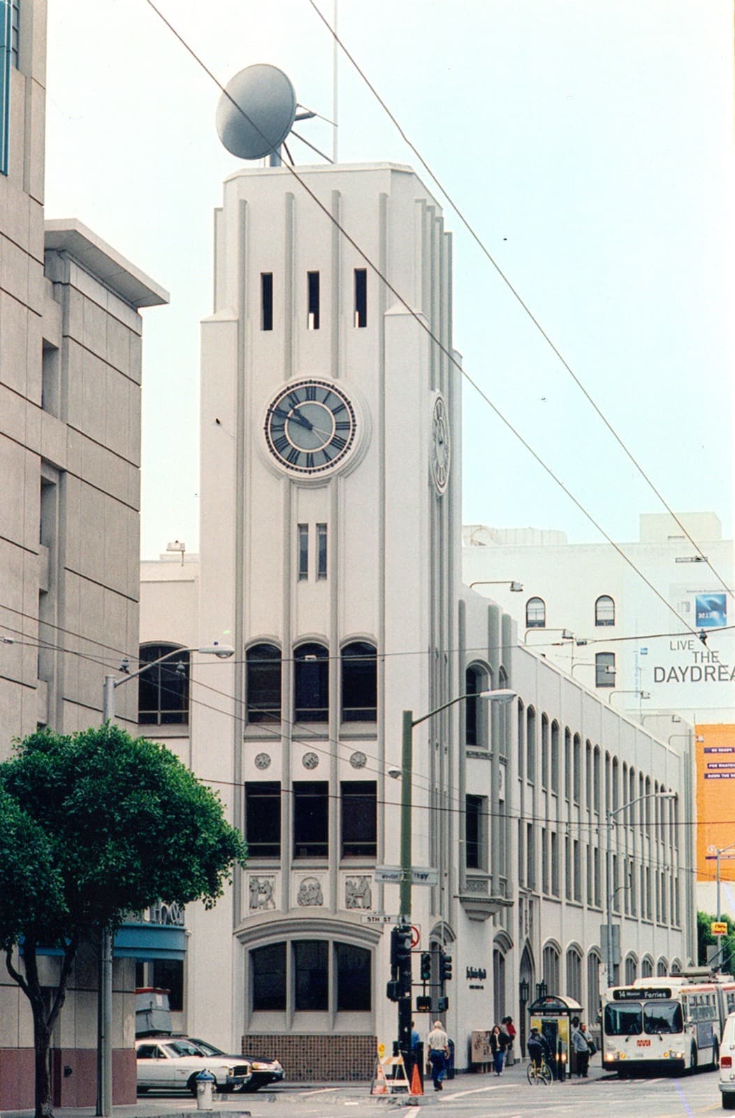 A pale clock-tower building on a street corner