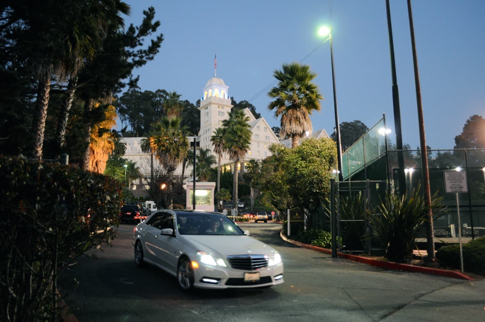 A white hotel tower rising behind palm trees at dusk