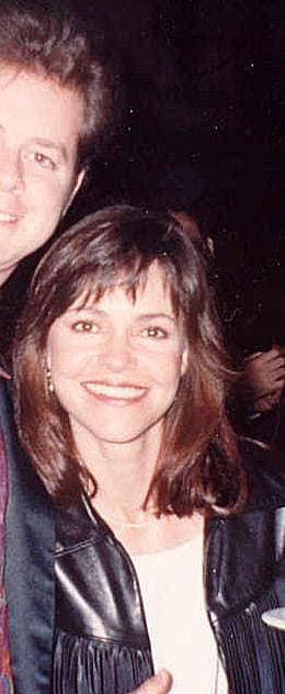 Sally Field smiling in a black leather jacket, holding a plate