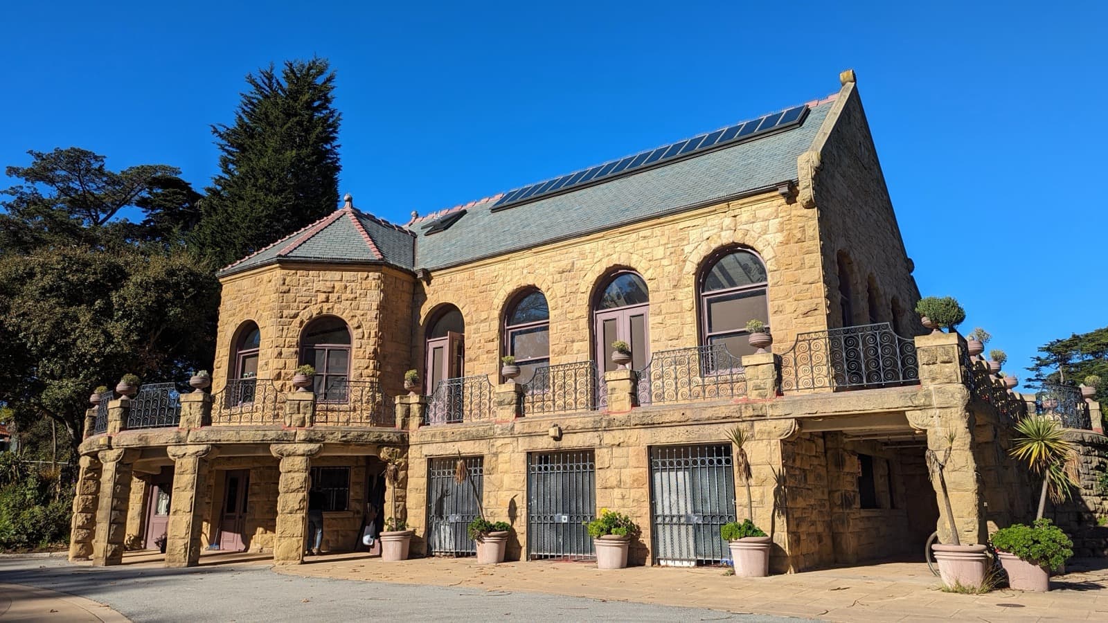 A stone building with arched windows under trees in Golden Gate Park