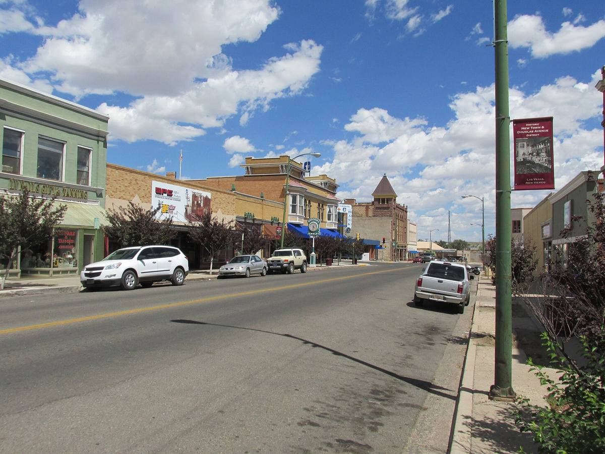 A wide street of low historic shopfronts under a bright sky