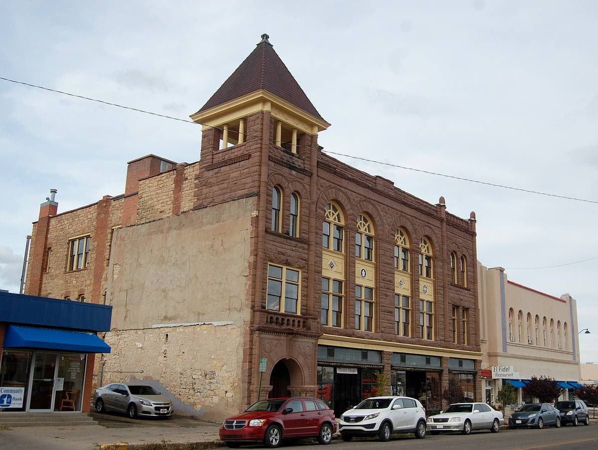 A tall brick building with a pointed turret on a corner