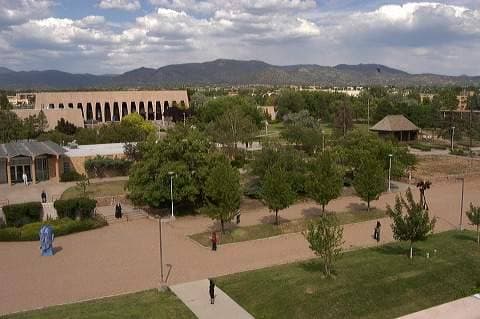A low adobe-style campus with lawns and paths, hills beyond