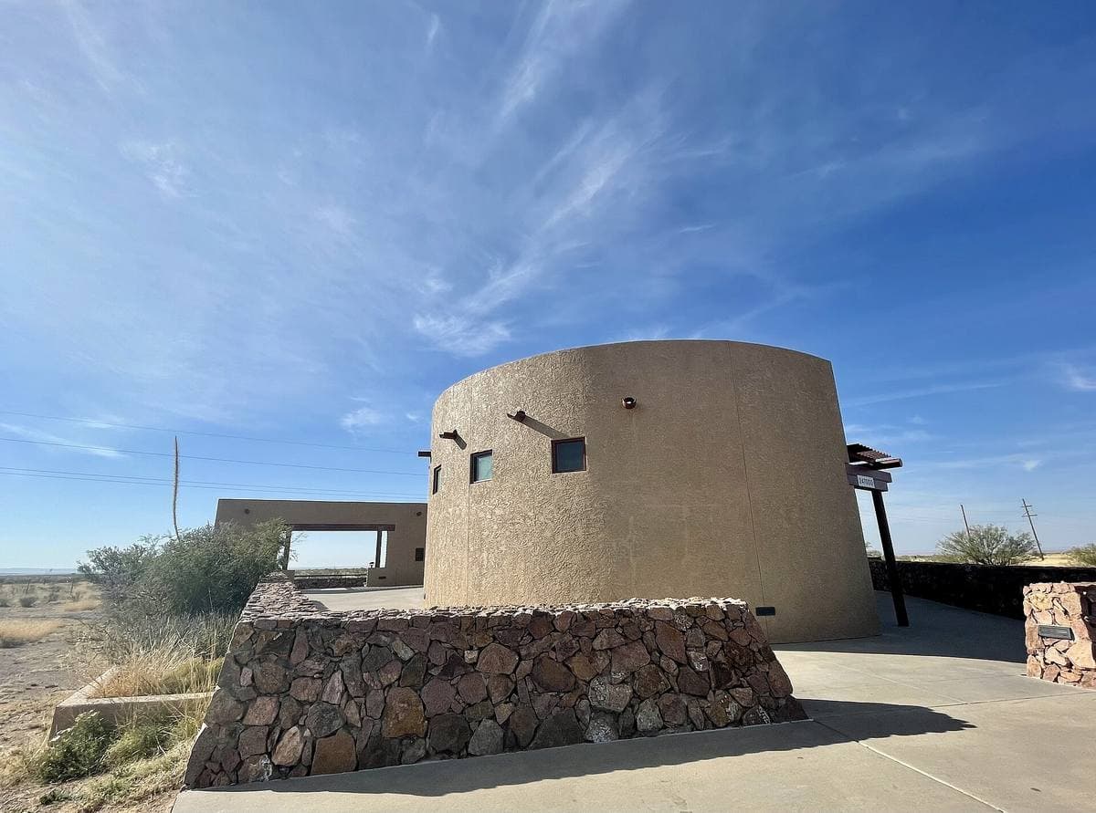 A round stone viewing platform on open grassland under a blue sky