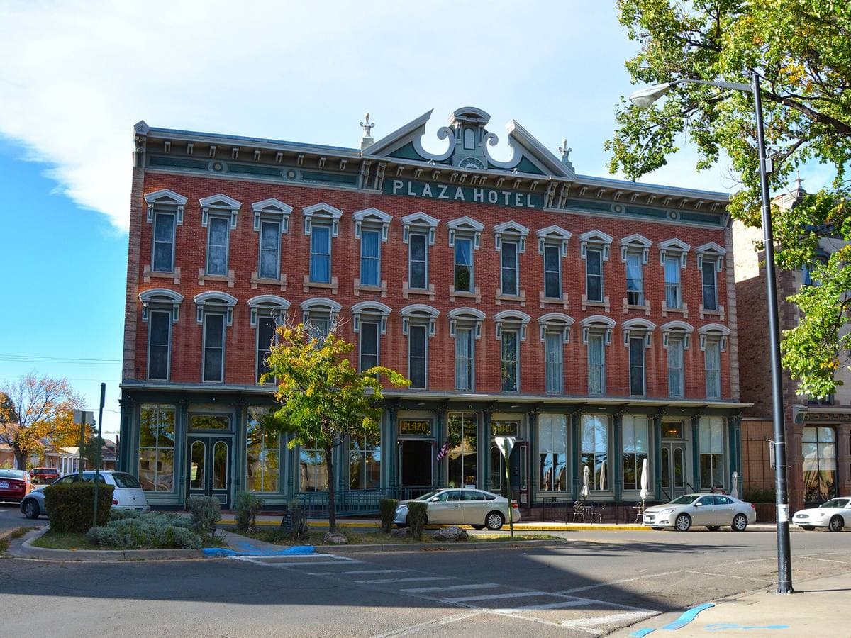 A three-storey red-brick Victorian hotel with an ornate parapet and striped awnings