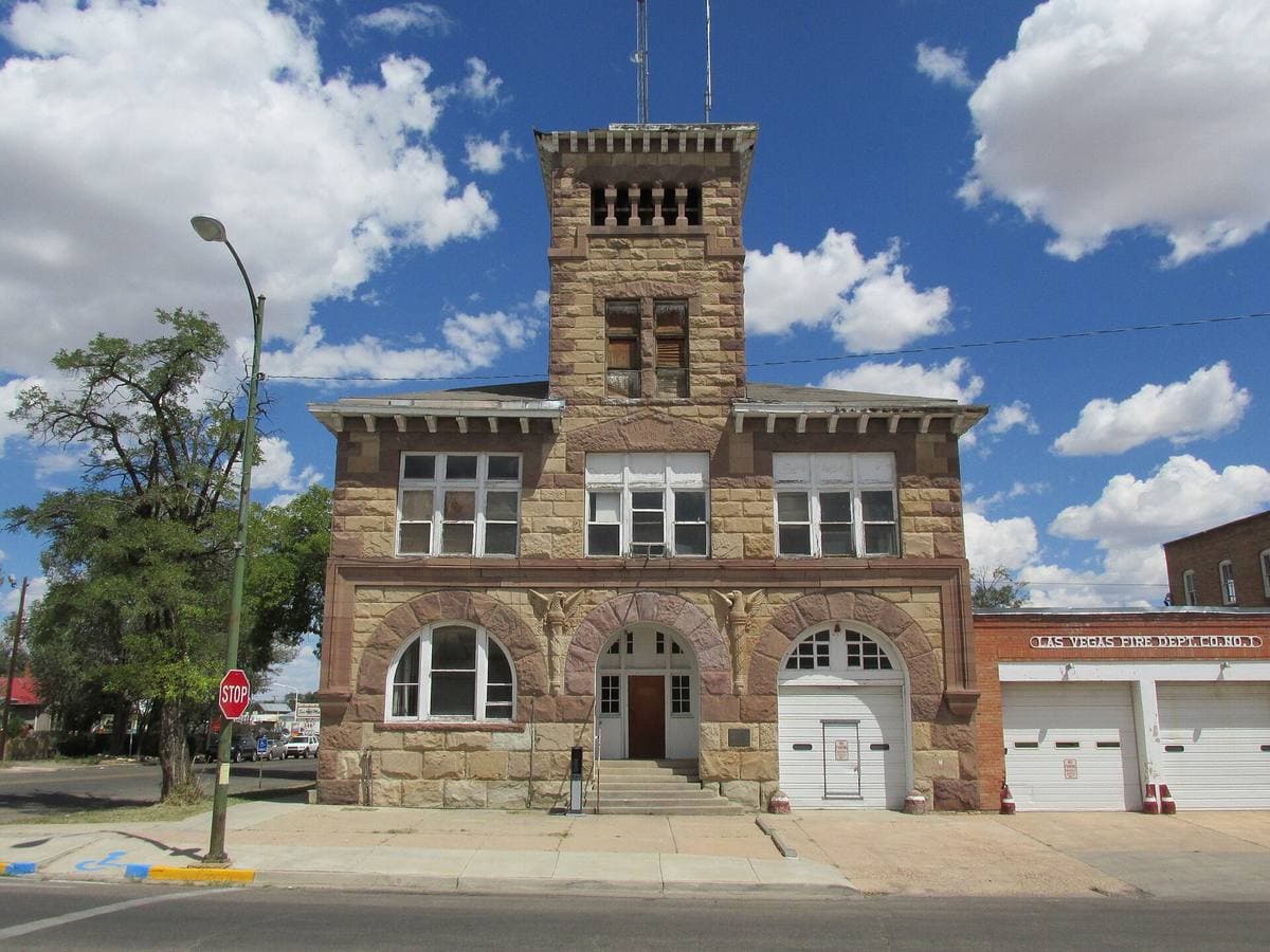A stone fire station with a square tower and two arched doors